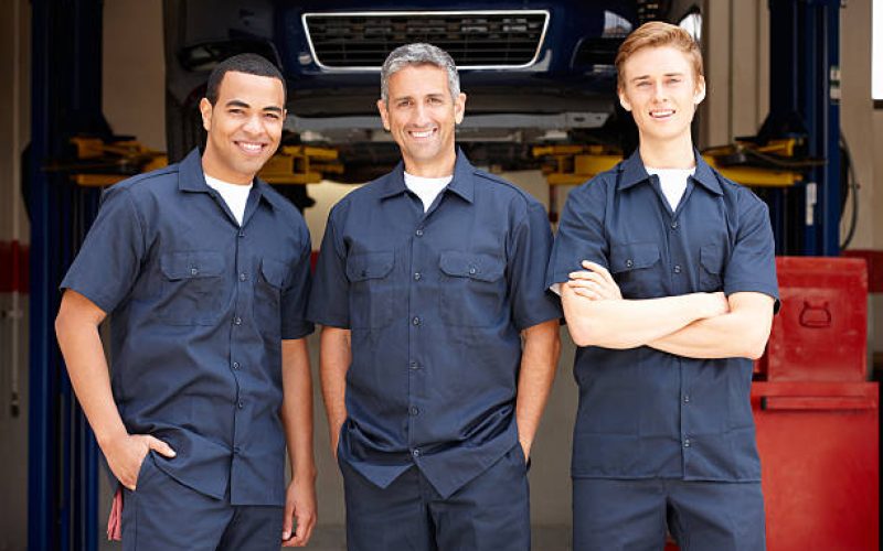 Three Male mechanics at work standing in workshop